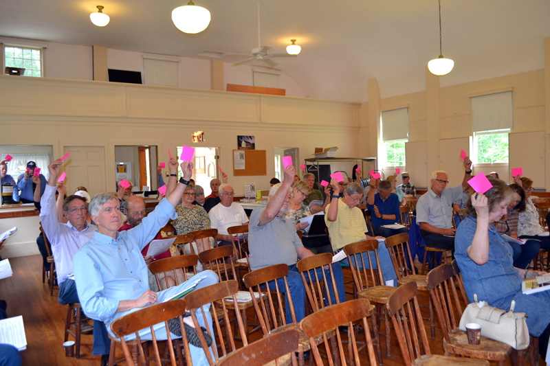 Westport Island voters raise their cards to support an article during annual town meeting at the historic town hall Saturday, June 24. (Charlotte Boynton photo)