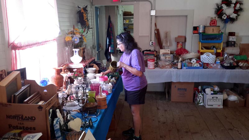 Jeanne Shaw, a volunteer with the Kings Mills Union Hall Association, arranges flower vases and art supplies for the organizations white elephant sale on July 4. (Photo courtesy Lucy Martin)