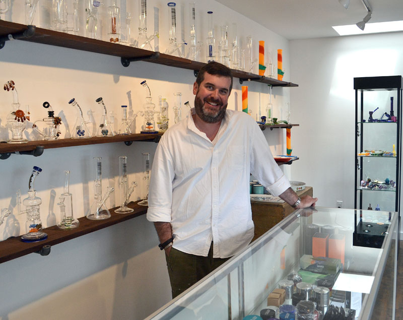 Sea Smoke Shop owner Penn Way stands behind the counter of his new glass pipe store in downtown Damariscotta. (Maia Zewert photo)