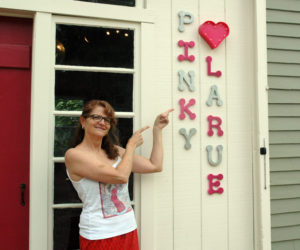 Natalie Masse points to a sign for her vintage store, Pinky Larue. The business will open Saturday, July 8. (Alexander Violo photo)