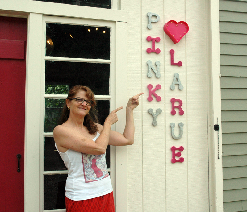 Natalie Masse points to a sign for her vintage store, Pinky Larue. The business will open Saturday, July 8. (Alexander Violo photo)