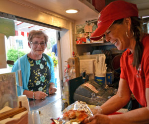 Red's Eats co-owner Debbie Gagnon serves one of the roadside stand's famous lobster rolls to a customer from Bethel on Tuesday, July 25. (Charlotte Boynton photo)