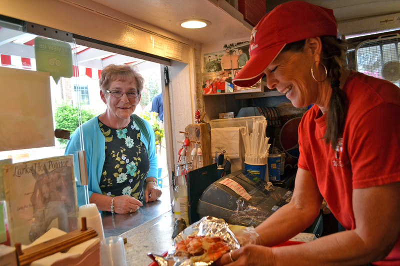 Red's Eats co-owner Debbie Gagnon serves one of the roadside stand's famous lobster rolls to a customer from Bethel on Tuesday, July 25. (Charlotte Boynton photo)