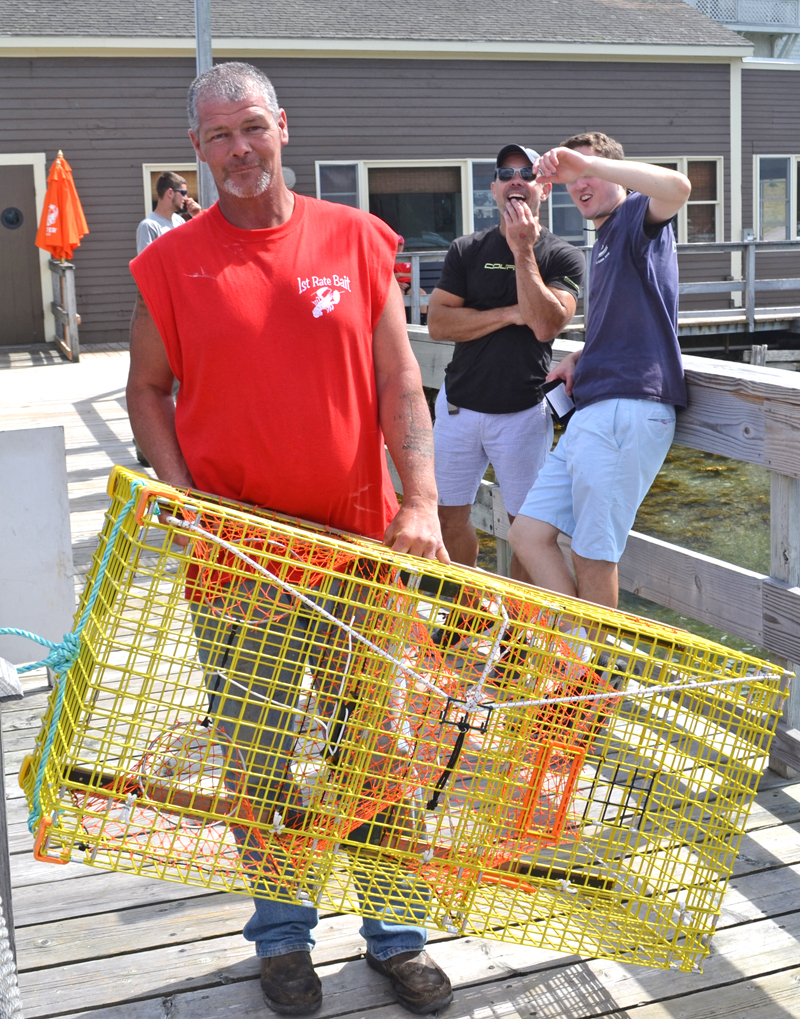 Brent Fogg, one of the organizers of the 31st annual Merritt Brackett Lobster Boat Races, brings a lobster trap to a lottery winner. (Abigail Adams photo)