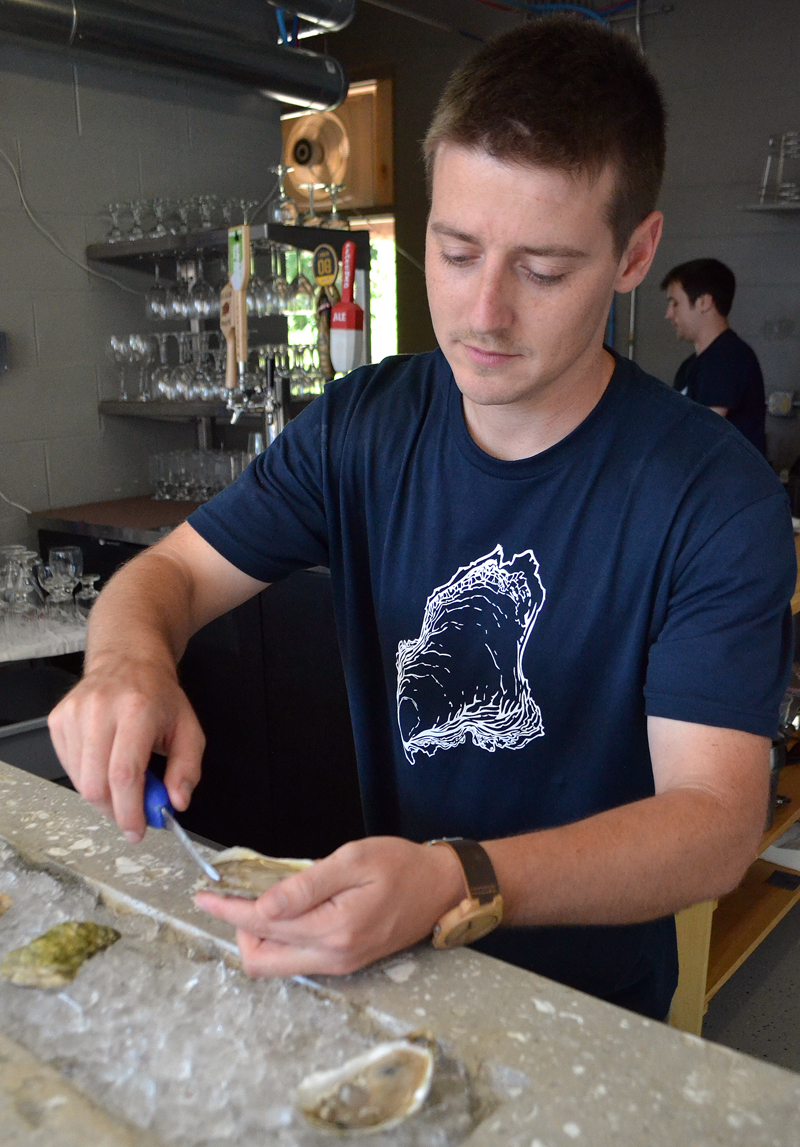 River Bottom Raw Bar owner Brendan Parsons shucks an oyster during the business's soft opening Sunday, Aug. 13. (Maia Zewert photo)