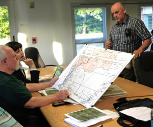 Waldoboro Board of Appeals members Natasha Irving and Russell Hansen (seated) review a zoning map of Jefferson and Elm streets in Waldoboro as architect Charles Campbell (right) looks on. (Alexander Violo photo)