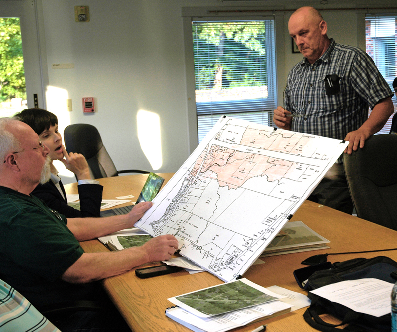 Waldoboro Board of Appeals members Natasha Irving and Russell Hansen (seated) review a zoning map of Jefferson and Elm streets in Waldoboro as architect Charles Campbell (right) looks on. (Alexander Violo photo)