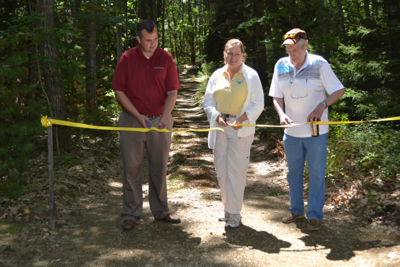 From left: David Seavey, Carrie Kinne, and George Richardson cut the ribbon at the Carl and Barbara Segerstrom Preserve at Squam Creek on Sunday, Aug. 6. The preserve on Westport Island is now open to the public. (Charlotte Boynton Photo)