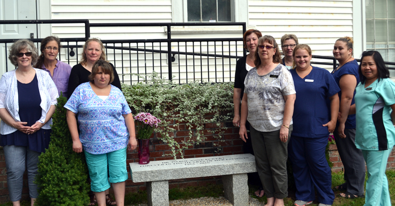 Sheepscot Valley Health Center staff members stand around Carol's Bench, which was dedicated to the memory of Dr. Carol Anne Eckert on Tuesday, Aug. 15. The bench will serve as a peaceful place for staff to sit and enjoy the outdoors. (Abigail Adams photo)