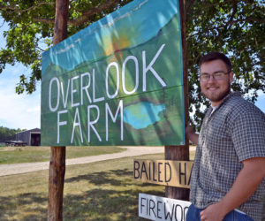 Ridge Barnes stands next to the sign for Overlook Farm. Barnes is the fifth generation of the Barnes family to run the farm. (Charlotte Boynton photo)