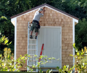 Peter Hallett nails the final shingle in place on the Ecumenical Diaper Bank's new storage house.