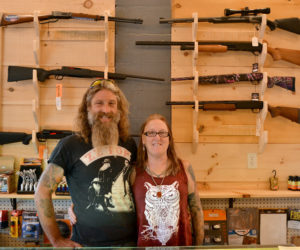 Dresden Take Out owners Mason and Kathy Dubord stand in front of a rack of firearms in the store's new gun room Tuesday, Oct. 10. (Maia Zewert photo)