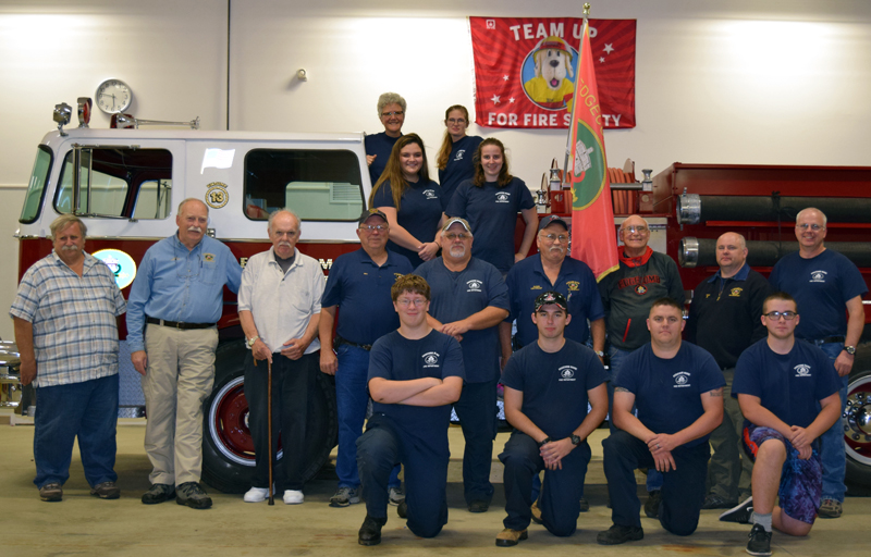 Edgecomb Fire Department members past and present pose for a photo at the fire station Thursday, Oct. 5. Front row from left: Aidan Tracey, Josh Kramley, Marc Babineau, and Ryan Potter. Middle: former Chief Barry Johnston, former Assistant Chief Larry Omland, Capt. Steve Fenton, Bill Witzell, Lt. Roland Abbott, Lt. Daren Graves, Capt. Tom Trowbridge, Assistant Chief John Potter, and Chief Roy Potter. Bottom row on truck: Ryann Trask and Leah Potter. Top row: Chaplain Kate Pinkham and Amanda Babineau. (J.W. Oliver photo)