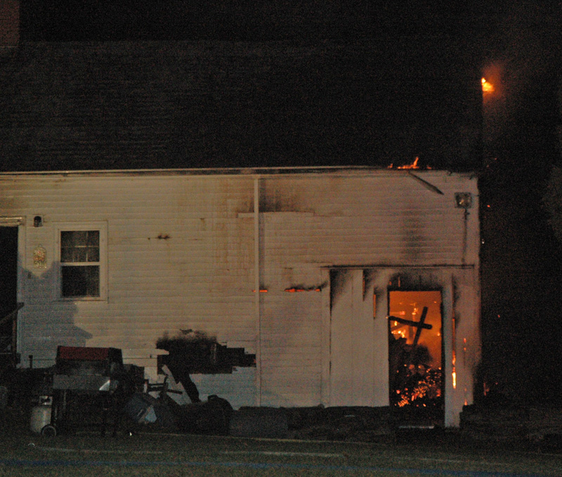 Flames are visible in a shed-like structure attached to the house. The fire started in the shed and spread to the main house. (Alexander Violo photo)