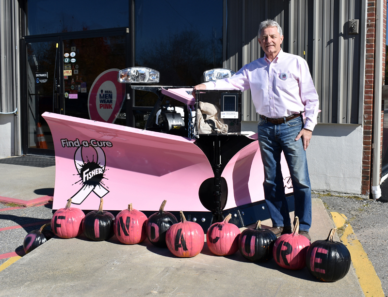 Randy Miller of Newcastle Chrysler Dodge Jeep Ram Viper stands at his dealership with a pink plow he is auctioning off.