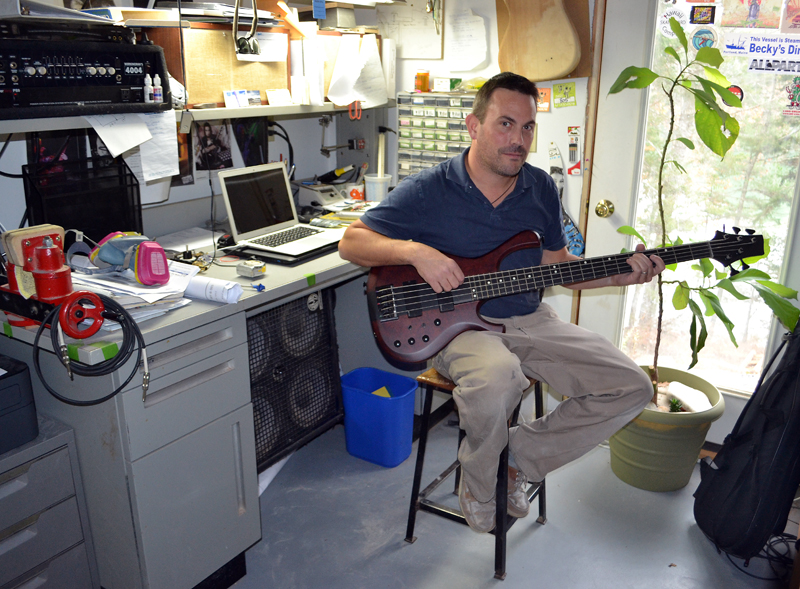 Jonathan Kelsey holds one of the guitars he built at JK Custom Woodworking in South Bristol. (Maia Zewert photo)