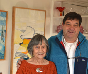 Round Pond artist Sally DeLorme Pedrick and gallery visitor Mark DesMeules stand before Pedrick's paintings "A Season of Chess" (left) and "North Wall" on Sunday, Dec. 3. (Christine LaPado-Breglia photo)