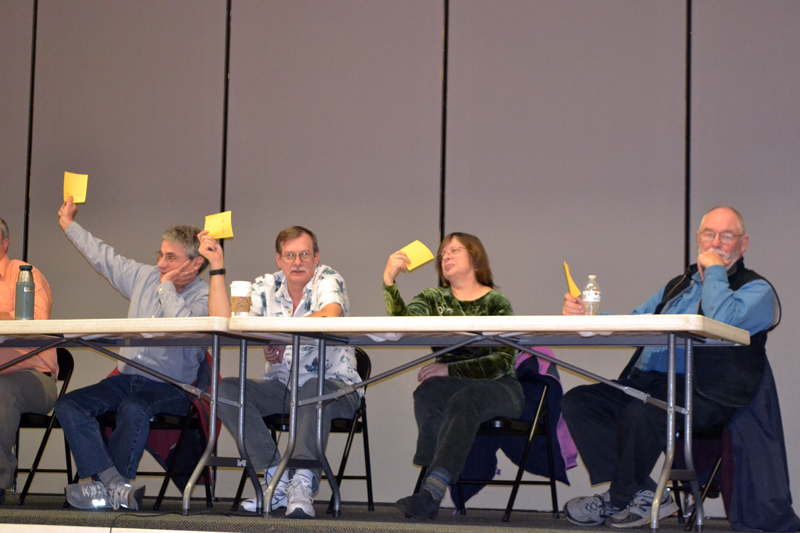 From left: Whitefield Selectmen Tony Marple, Lester Sheaffer, Charlene Donahue, and Frank Ober raise their cards to vote for a 180-day moratorium on marijuana establishments during a special town meeting at Whitefield Elementary School on Wednesday, Dec. 6. (Christine LaPado-Breglia photo)