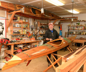 Rob Macks easily lifts a 28-pound kayak he made in his Laughing Loon workshop in Jefferson. (Paula Roberts photo)