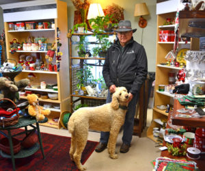 Guy Thompson, owner of First Class Florals and All the Comforts, stands in the middle of the store with his dog, Jessy. The store will close Friday, Jan. 5. (Maia Zewert photo)