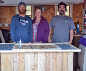From left: Chase Morrill, Ashley Morrill-Eldridge, and Ryan Eldridge stand in front of a mobile shucking station built for a renovated cabin at Glidden Point Oyster Farm in Edgecomb. (LCN file photo)