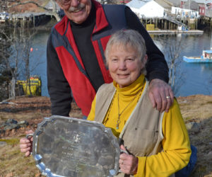 Ron and Jeri Pendleton pose for a photo outside their New Harbor home with a silver platter, a gift in recognition of their 100 years of service to Bristol Fire and Rescue. (Maia Zewert photo)