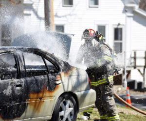 Damariscotta firefighter Chris Hilton works to put out a car fire next to the Damariscotta United Methodist Church on Monday, April 23. (Jessica Picard photo)