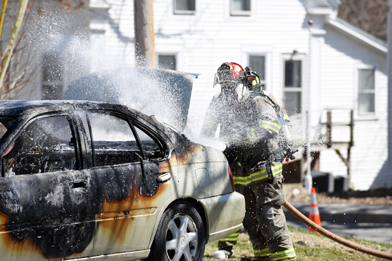 Damariscotta firefighter Chris Hilton works to put out a car fire next to the Damariscotta United Methodist Church on Monday, April 23. (Jessica Picard photo)