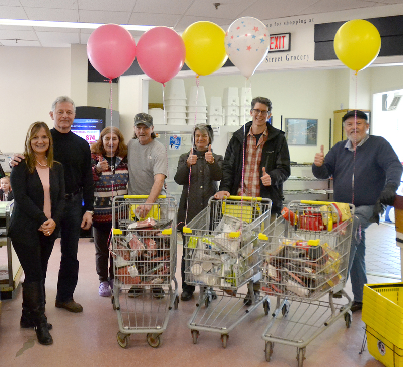 Main Street Grocery owner Jane Gravel and Newcastle Chrysler Dodge Jeep Ram Viper President Randy Miller stand beside the recipients of a 60-second shopping spree Saturday, April 7. From left: Gravel, Miller, Tammy Piper, Paul Gagnon, Lucy Smith, Doug Straus, and the Rev. Tom Wagers. (Maia Zewert photo)