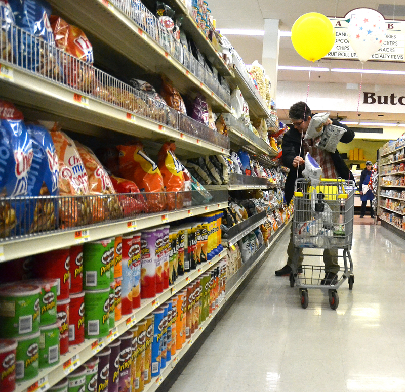 Healthy Kids Board of Directors member Doug Straus flings bags of chips into his cart during a 60-second shopping spree at Main Street Grocery on Saturday, April 7. (Maia Zewert photo)