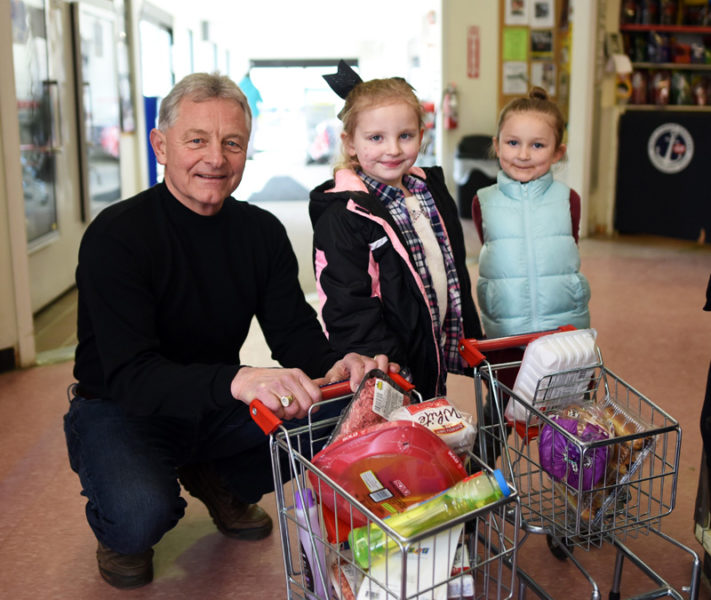 Randy Miller, of Newcastle Chrysler Dodge Jeep Ram Viper, poses with Aria Davis, 4, and Brooklyn Beal, 5, after a shopping spree at Main Street Grocery on Saturday, April 7. After the spree, the girls mimicked the event, running through the store with their miniature shopping carts. (Jessica Picard photo)