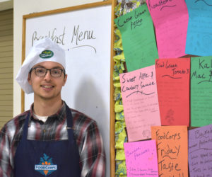 FoodCorps service member Jared Grenier stands next to recipes for a recent FoodCorps Friday at Medomak Middle School in Waldoboro. On FoodCorps Fridays, students taste-test and rate different foods. (Alexander Violo photo)