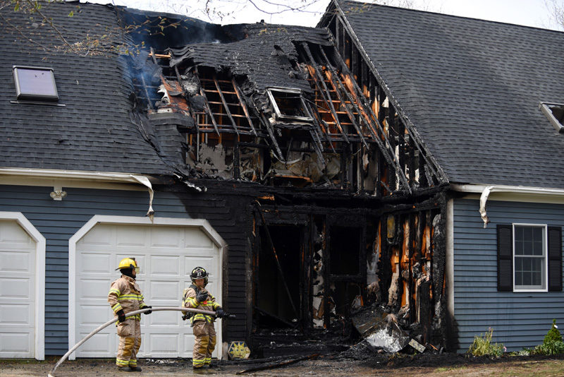 A pair of firefighters stands by during the response to a house fire at 12 Woods Lane in Damariscotta the afternoon of Thursday, May 10. (Jessica Picard photo)