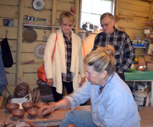 Cindy and Bill Anderson, who split their time between Palm Coast, Fla. and Spruce Head, watch as Libbey Seigars demonstrates the Japanese pottery-making style of "throwing from the mound" at Whitefield Pottery on Sunday, May 6 during the Maine Pottery Tour. (Christine LaPado-Breglia photo)