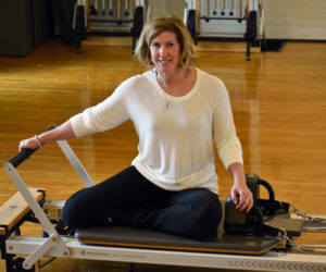 Jessica Daly sits on a Pilates reformer at Ocean Blue Pilates Yoga, her new studio in the former Nobleboro Grange meeting hall. (Alexander Violo photo)