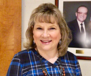 Linda Pease poses in front of a photo of her father, the late Ronald Doloff, Medomak Valley High School principal from 1970-1994. Pease will begin the same job in July after six months in an acting role. (Photo courtesy Lisa Genthner Gunn)