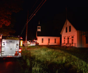 Firefighters and trucks at the scene of a fire on Dutch Neck Road in Waldoboro late Thursday, June 14. The buildings visible are the historic St. Paul's Union Chapel and Dutch Neck Schoolhouse. The fire was at a house on a driveway behind those buildings. (J.W. Oliver photo)