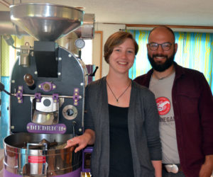 Monhegan Coffee Roasters co-owners Carley Mayhew and Mott Feibusch stand next to their coffee roaster in the business's headquarters on Monhegan Island. (Maia Zewert photo)