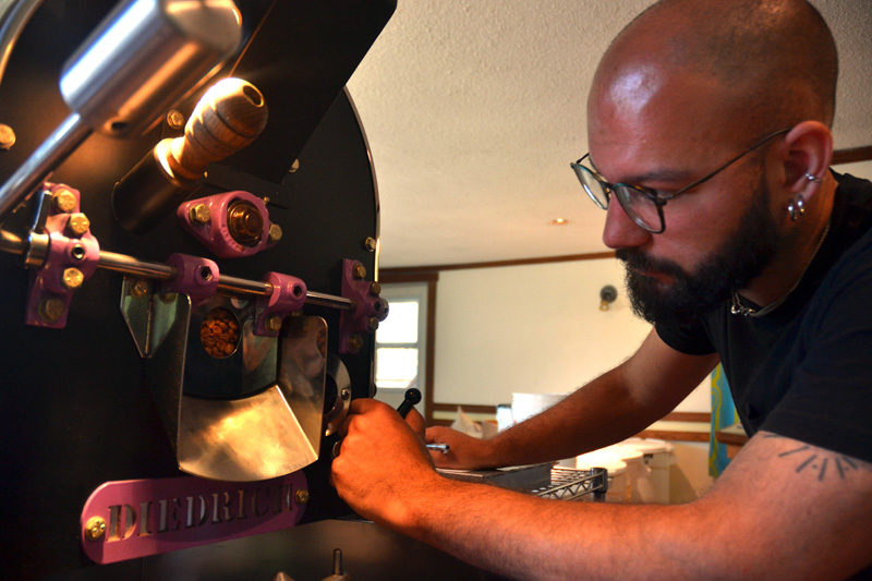 Monhegan Coffee Roasters co-owner Mott Feibusch checks the color of coffee beans during the roasting process. (Maia Zewert photo)