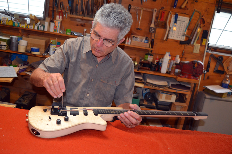 Ned Steinberger adjusts the bridge on a guitar in his Nobleboro workshop. (Christine LaPado-Breglia photo)