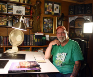 Artist Glenn Chadbourne sits in his home office in Newcastle, surrounded by books he has illustrated, including many by famed horror author Stephen King. (Jessica Picard photo)