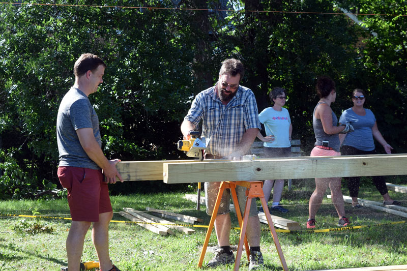 Charles Leitzell (left) and Jason Putnam work together to saw a beam for a new outdoor classroom at Wiscasset Elementary School. (Jessica Clifford photo)