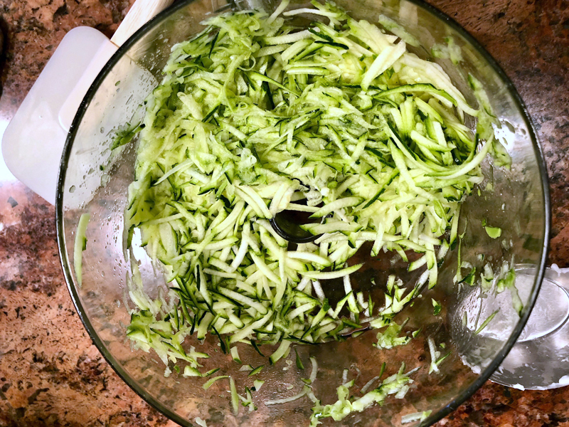 Shredded zucchini  press out the excess moisture with the base of a Manhattan glass, being careful not to spill. (Photo courtesy Lise Roy)