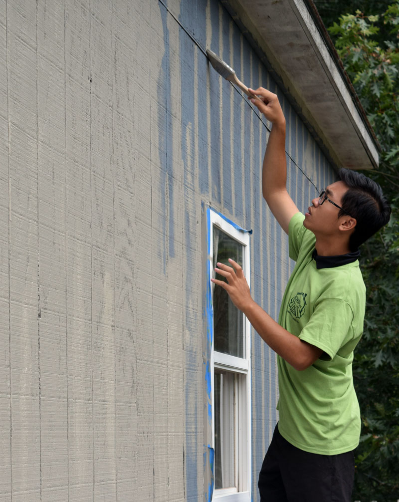 Lincoln Academy senior William Doan paints Shannon Bailey's garage. (Jessica Clifford photo)