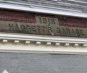 A subcontractor will remove the Haggett's Garage sign and the bricks around it before it demolishes the 1916 building to make room for a parking lot. (Charlotte Boynton photo)