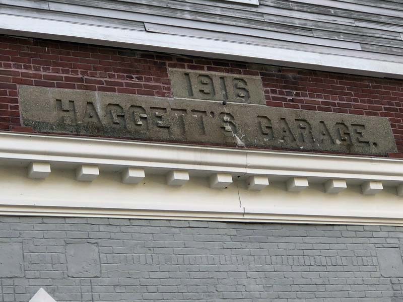 A subcontractor will remove the Haggett's Garage sign and the bricks around it before it demolishes the 1916 building to make room for a parking lot. (Charlotte Boynton photo)