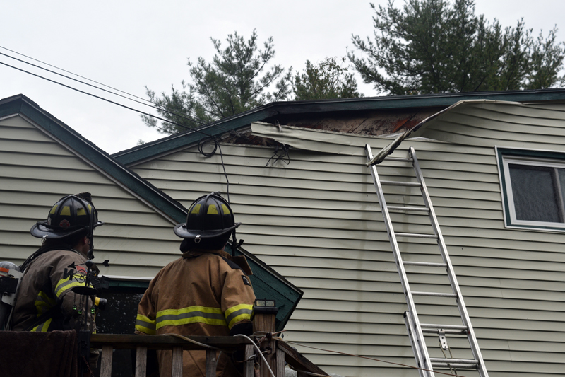 Firefighters examine damage to the siding of a home on Cooper Road in Whitefield after extinguishing an electrical fire the afternoon of Monday, Oct. 1. There were no injuries as a result of the fire. (Jessica Clifford photo)