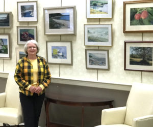 Kay Hannah stands before a wall of her artwork.