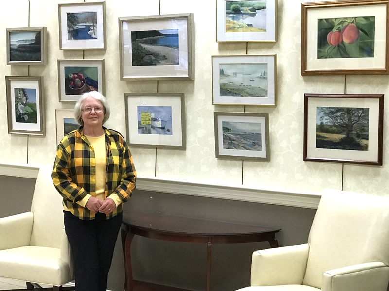 Kay Hannah stands before a wall of her artwork.