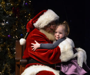 Elodie Page, 4, of Damariscotta, gives Santa a hug after informing him of her Christmas wishes at the Lincoln Theater on Saturday, Nov. 24. (Maia Zewert photo)